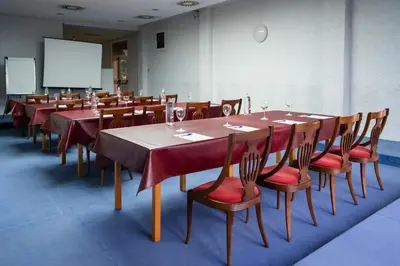 a conference room with long tables and chairs and a screen at Hotel Bartos in Almussafes