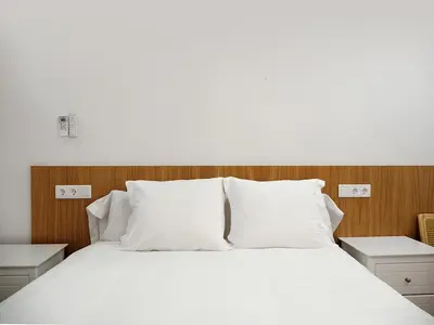 a white bed with white pillows and a wooden headboard at Hotel Casbah in El Puig