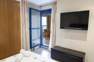 a hotel room with a bed and a flat screen tv at ApartUP Patacona Oriental in Valencia