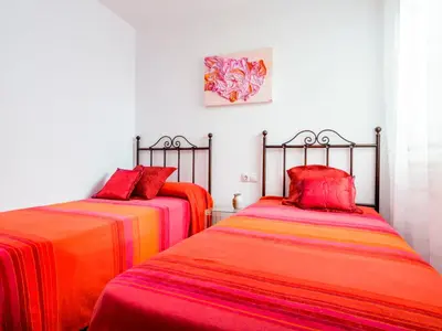 two beds in a room with red and orange sheets at Apartment Jardimar by Interhome in Moncófar