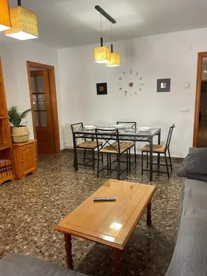 a dining room with a table and chairs and a clock at UIM Mediterraneo M Cristina con garaje Wifi in Puerto de Sagunto