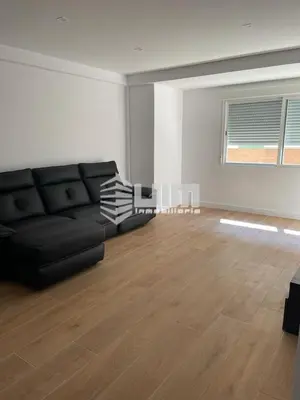 a living room with a black couch and a wooden floor at UIM Mediterraneo Conqueridor Wifi in Sagunto