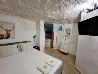a bedroom with a white bed and a tv at Preciosa casa-cueva con bañera in Paterna
