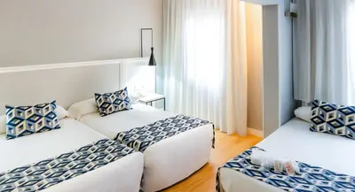 a hotel room with two beds with blue and white pillows at Hotel Beleret in Valencia