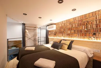 a bedroom with two beds and a large wall of books at Loft con carácter en Valencia. in Valencia