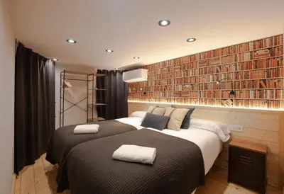 a bedroom with a large bed and a large wall of books at Loft con carácter en Valencia. in Valencia
