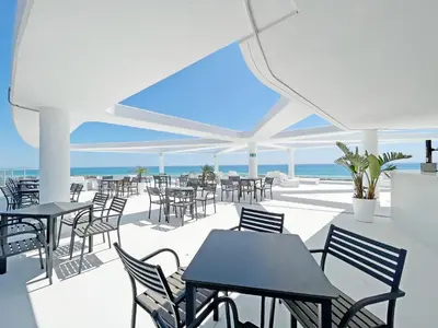 an empty patio with tables and chairs and the ocean at Global Vacacional, Moderno apartamento de dos terrazas con vistas al mar y a la montaña in Canet de Berenguer
