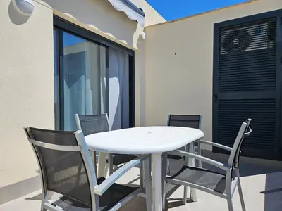 a white table and chairs in front of a building at Realrent Neo Mediterráneo in Barrio-Mar