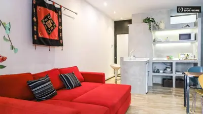 a living room with a red couch and a kitchen at Pequeño Loft en Ruzafa wifi in Valencia