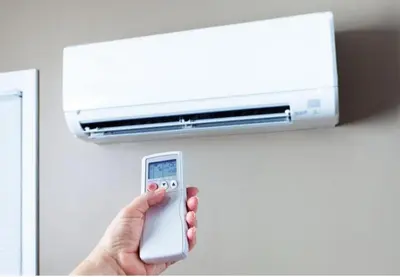 a person holding a remote control in front of a air conditioner at UIM Mediterraneo Virgen del Carmen 1 Wifi in Puerto de Sagunto