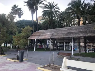 a pavilion with a bench in a park with palm trees at A 50 m de la plage in Cullera