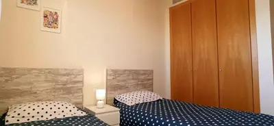 a bedroom with two beds and a wooden cabinet at Apartamento Aguamarina - Playa Moncofa in Moncófar