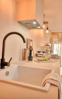a kitchen sink with a bottle of wine and wine glasses at Suite con Jacuzzi en la montaña. in Llombay