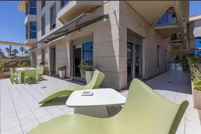 a patio with green chairs and a table and a building at luxury sea view apartment with 2 rooms in Valencia