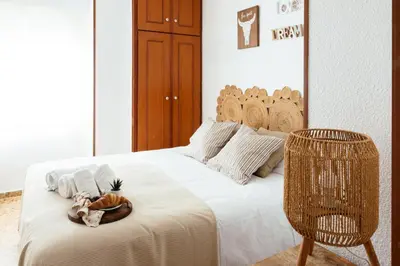 a bedroom with a white bed with a wicker chair at Almar Collection Cullera AR in Cullera