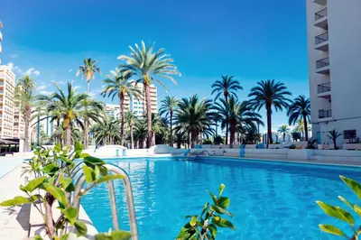 a swimming pool with palm trees and buildings at Almar Collection Cullera AR in Cullera