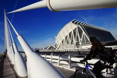 a woman riding a bike in front of a stadium at Hotel Medium Valencia in Valencia