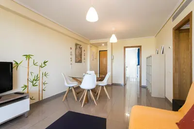 a dining room and living room with a table and chairs at ApartUP Patacona Orchard Views in Valencia