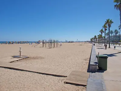 a sandy beach with palm trees and a playground at ApartUP Patacona Orchard Views in Valencia
