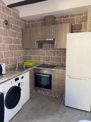 a kitchen with white appliances and a brick wall at La carchata 1 in Siete Aguas