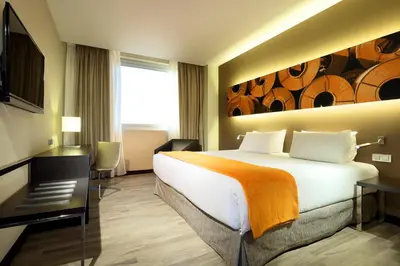 a hotel room with a bed and a desk and a room at Exe Puerto de Sagunto in Puerto de Sagunto