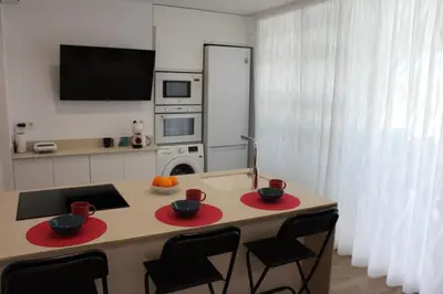 a kitchen with a table with two chairs and a kitchen with a tv at Apartamento a pie de playa in Cullera