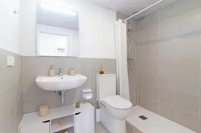 a white bathroom with a toilet and a sink at Global Vacacional, Apartamento con terraza y vistas a la piscina en Gran Canet in Canet de Berenguer