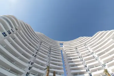 a tall white building with a blue sky in the background at Global Vacacional, Apartamento con terraza y vistas a la piscina en Gran Canet in Canet de Berenguer