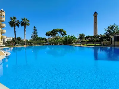 a large blue swimming pool with a tower in the background at Global Vacacional, Apartamento con terraza y piscina en la playa de Canet in Canet de Berenguer
