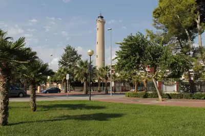 a lighthouse in the middle of a park with trees at Global Vacacional, Apartamento con terraza y piscina en la playa de Canet in Canet de Berenguer