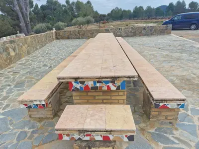 a wooden bench with tiles on it in a parking lot at El-cortijo in Siete Aguas