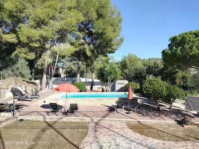 a swimming pool with chairs and a red umbrella at Casa Mas Montañas in Godelleta