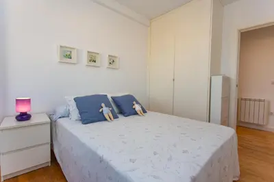 a white bedroom with a bed with two dolls on it at Cullera Beach Apartment Cap Blanc in Cullera