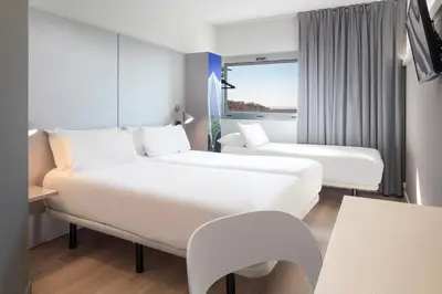 a hotel room with two beds and a window at B&B HOTEL Valencia Aeropuerto in Paterna