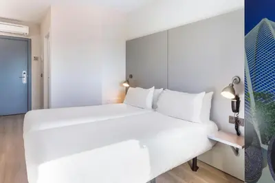 a bedroom with a large white bed with white pillows at B&B HOTEL Valencia Aeropuerto in Paterna