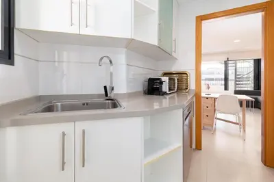 a kitchen with white cabinets and a sink at ApartUP Patacona Sunrise Duplex I in Valencia