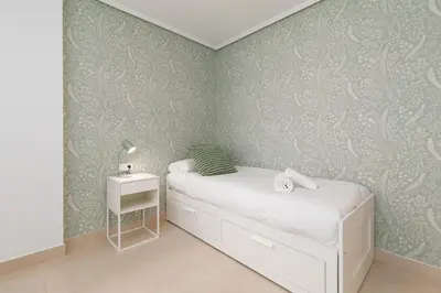 a small bedroom with a bed and a side table at ApartUP Patacona Sunrise Duplex I in Valencia