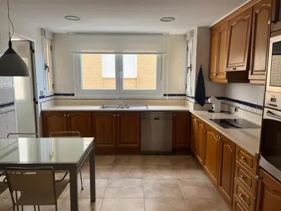 a kitchen with wooden cabinets and a table and a window at FRENTE AL MAR in Burriana