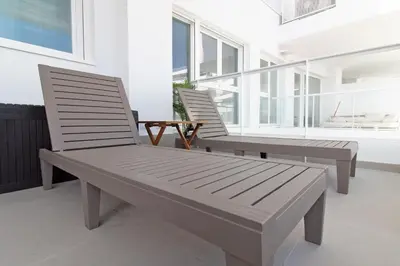 two benches sitting on a balcony with windows at Global Vacacional, Apartamento con terraza y vistas a la costa mediterránea in Canet de Berenguer