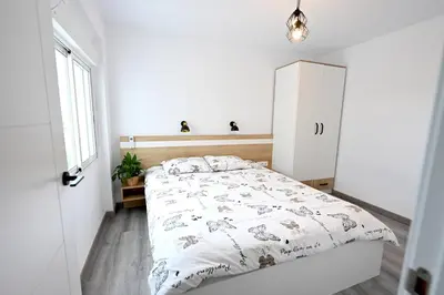 a white bedroom with a bed and a window at Victoria Apartment in Puerto de Sagunto