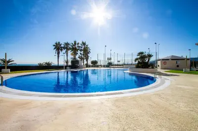 a large blue swimming pool with palm trees in the background at ESPACIO 8 - Primera Línea de Playa in Cullera