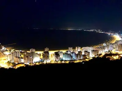 a view of a city at night with the ocean at Racó de la Mar in Faro de Cullera
