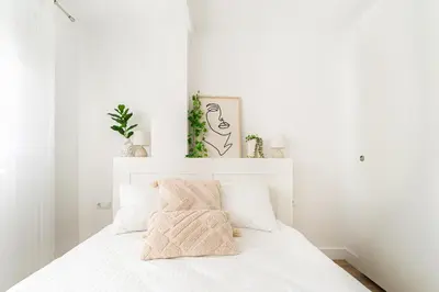 a white bedroom with a bed with white walls and plants at Espectacular piso reformado al lado del rio Turia in Valencia