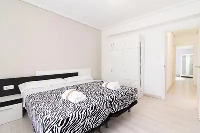 a white bedroom with a black and white bed at Global Vacacional, Apartamento de 4 habitaciones a 100 m de la playa in Puerto de Sagunto