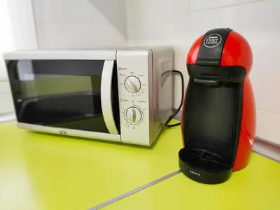 a red and black coffee maker next to a microwave at Global Vacacional, Apartamento de 4 habitaciones a 100 m de la playa in Puerto de Sagunto