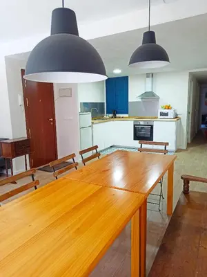 a kitchen with a wooden table and two pendant lights at Vistas a las palmeras in Burjasot